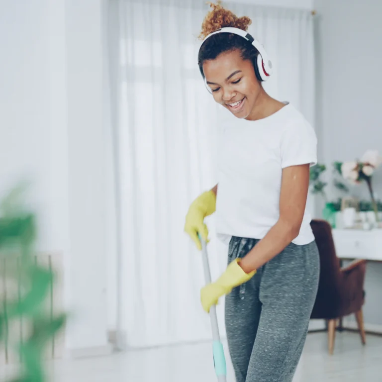 Smiling cleaner in yellow gloves mopping a bright living room